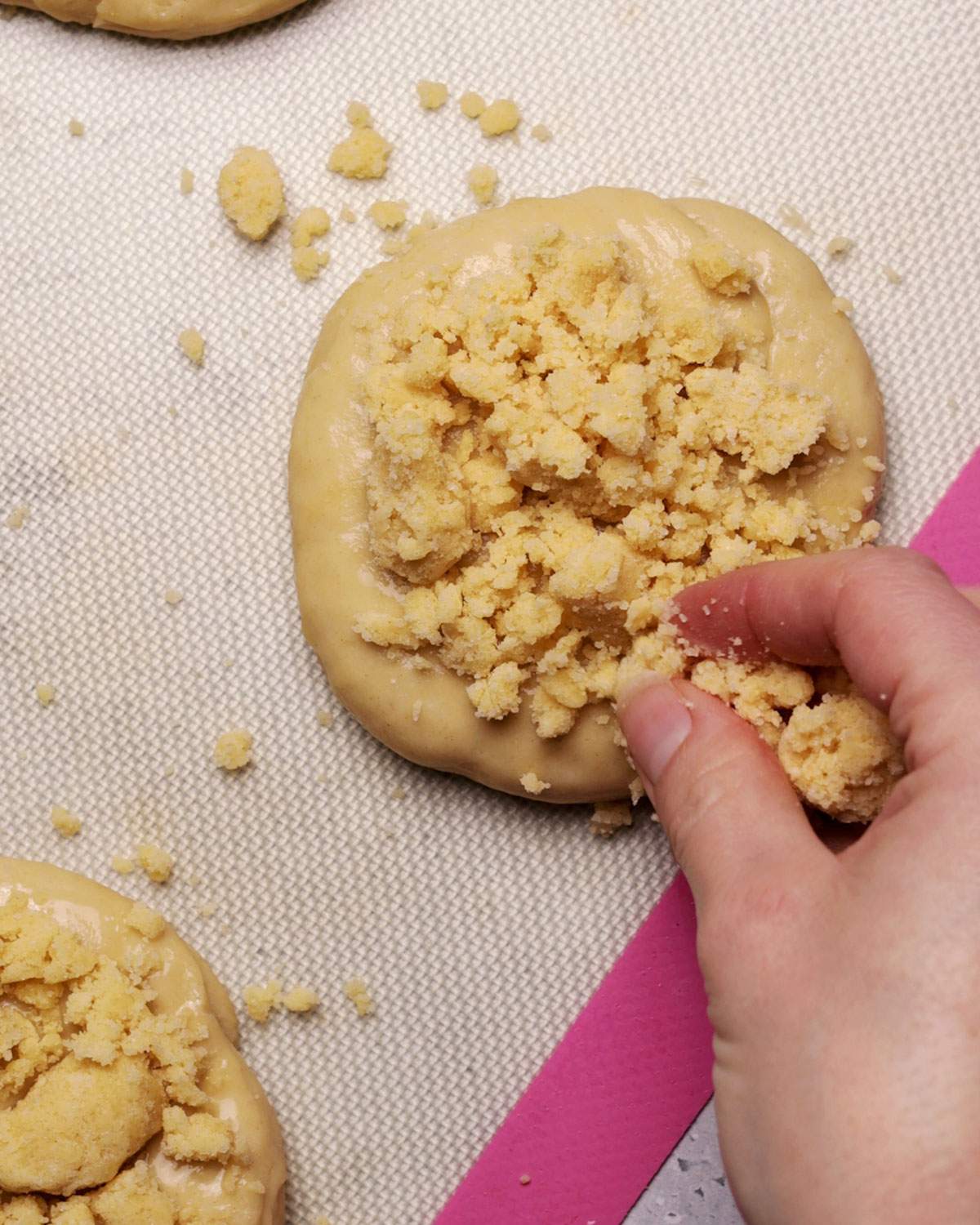 Adding crumble mixture onto dough rolls.