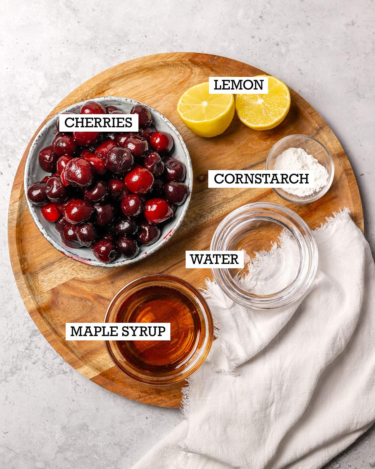 Ingredients for cherry compote on a wooden tray with labels.
