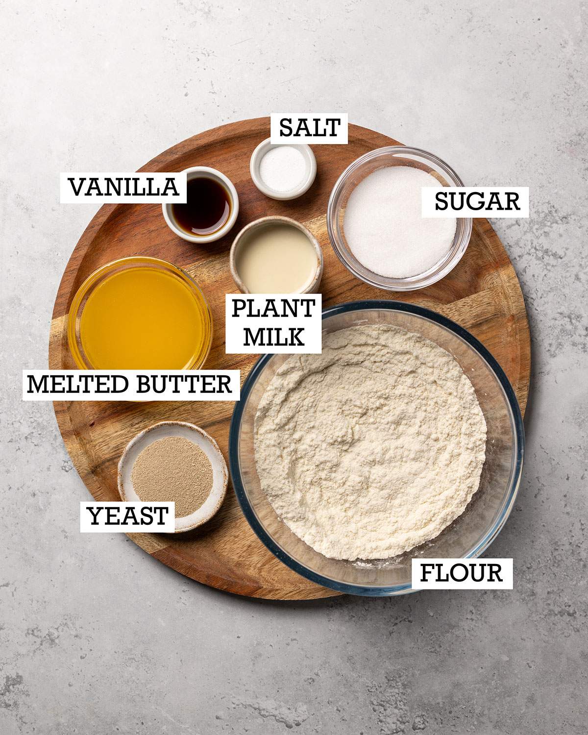Ingredients for vegan yeast dough on a wooden tray with labels.