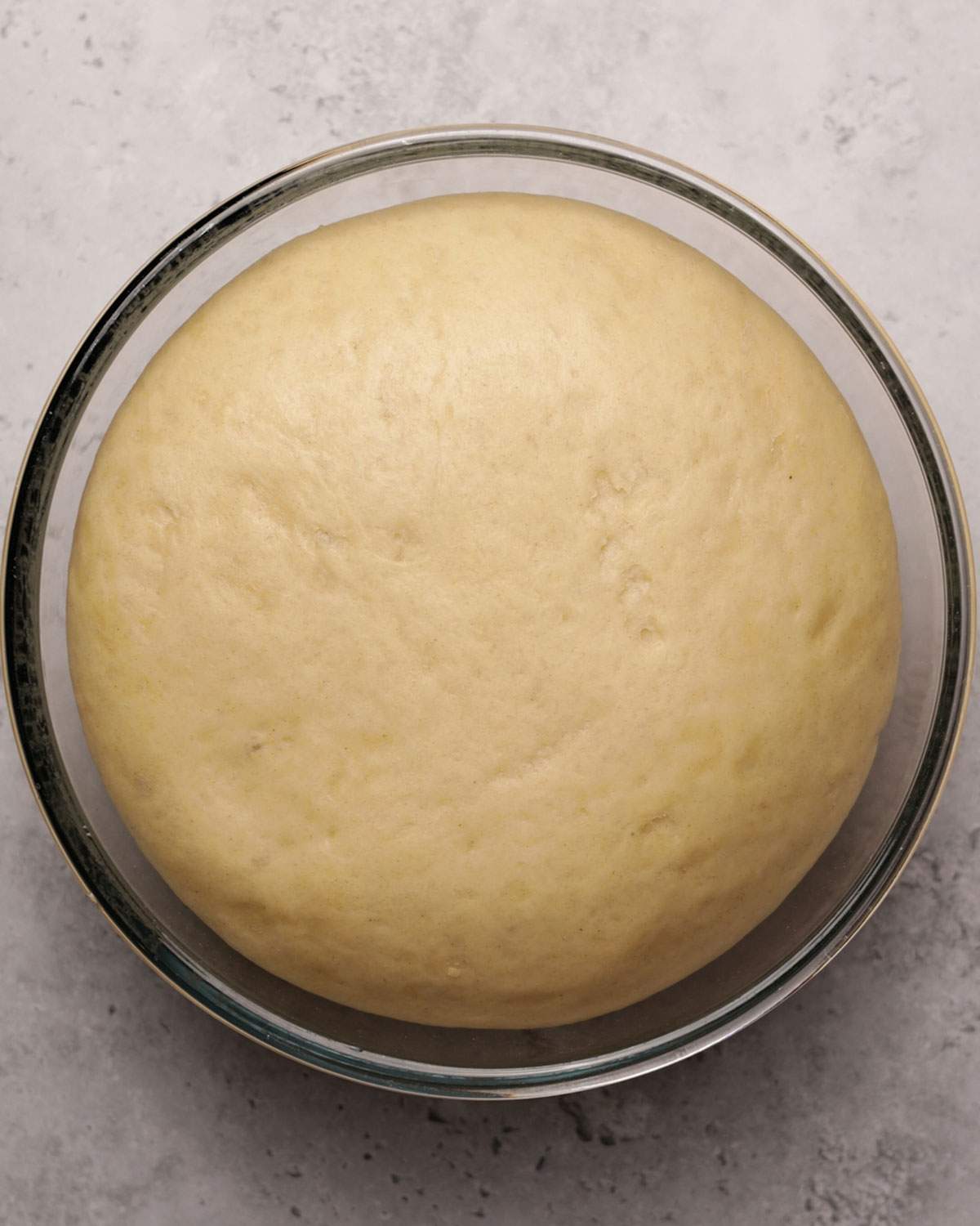 Risen yeast dough in a glass bowl.