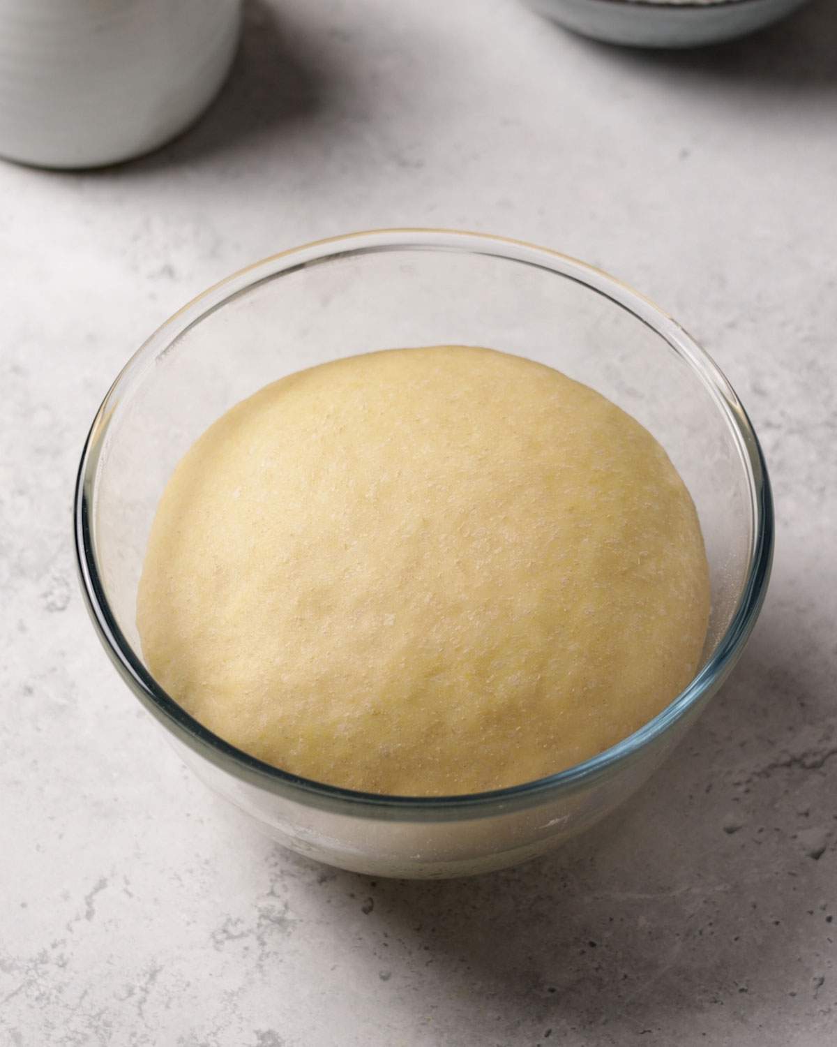 Risen yeast dough in a glass bowl.