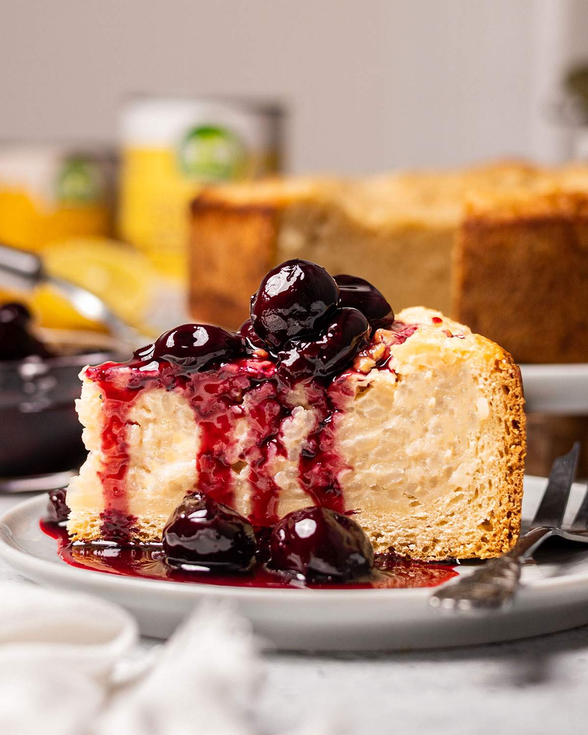 A slice of vegan baked rice pudding cake aka vegan Reisfladen on a plate with cherries.