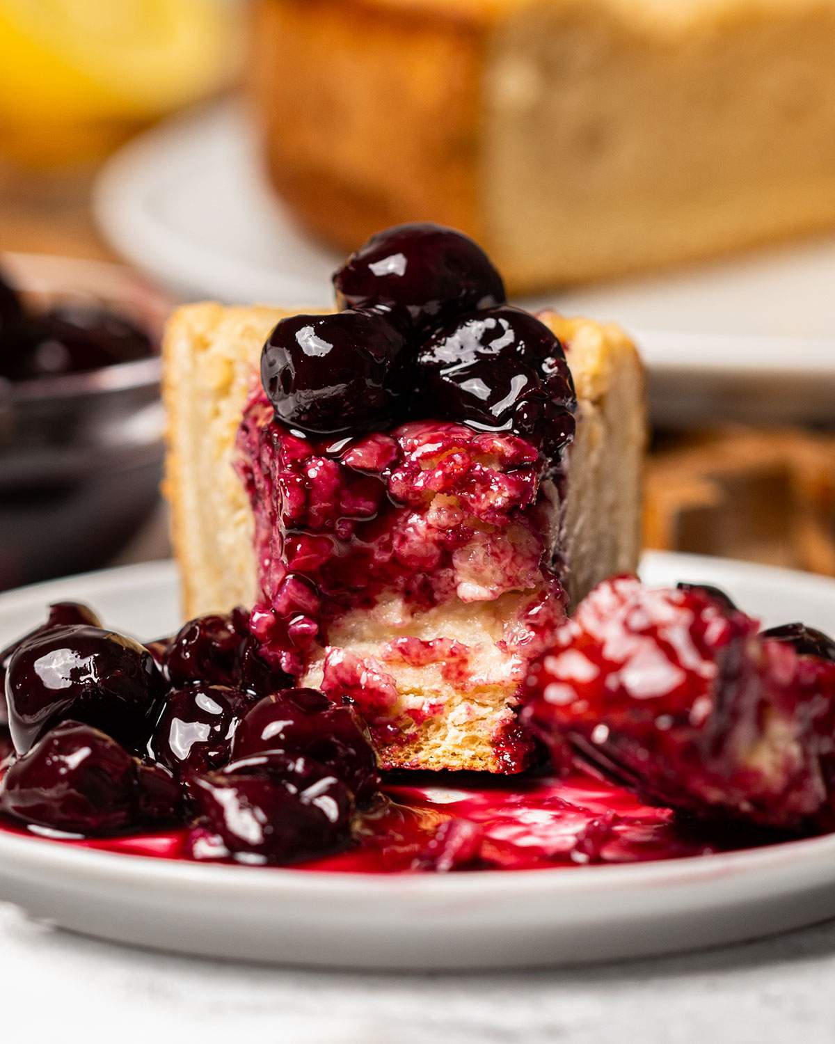 A slice of vegan Reisfladen with cherries on a serving plate with the front already eaten.