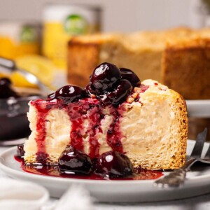A slice of vegan baked rice pudding cake aka vegan Reisfladen on a plate with cherries.