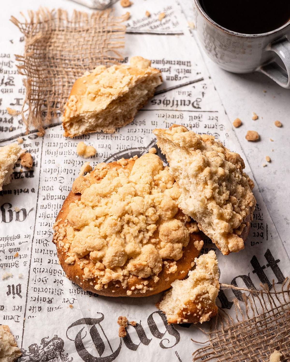 Vegan crumble rolls on parchment paper with one torn apart showing the fluffy dough texture inside.