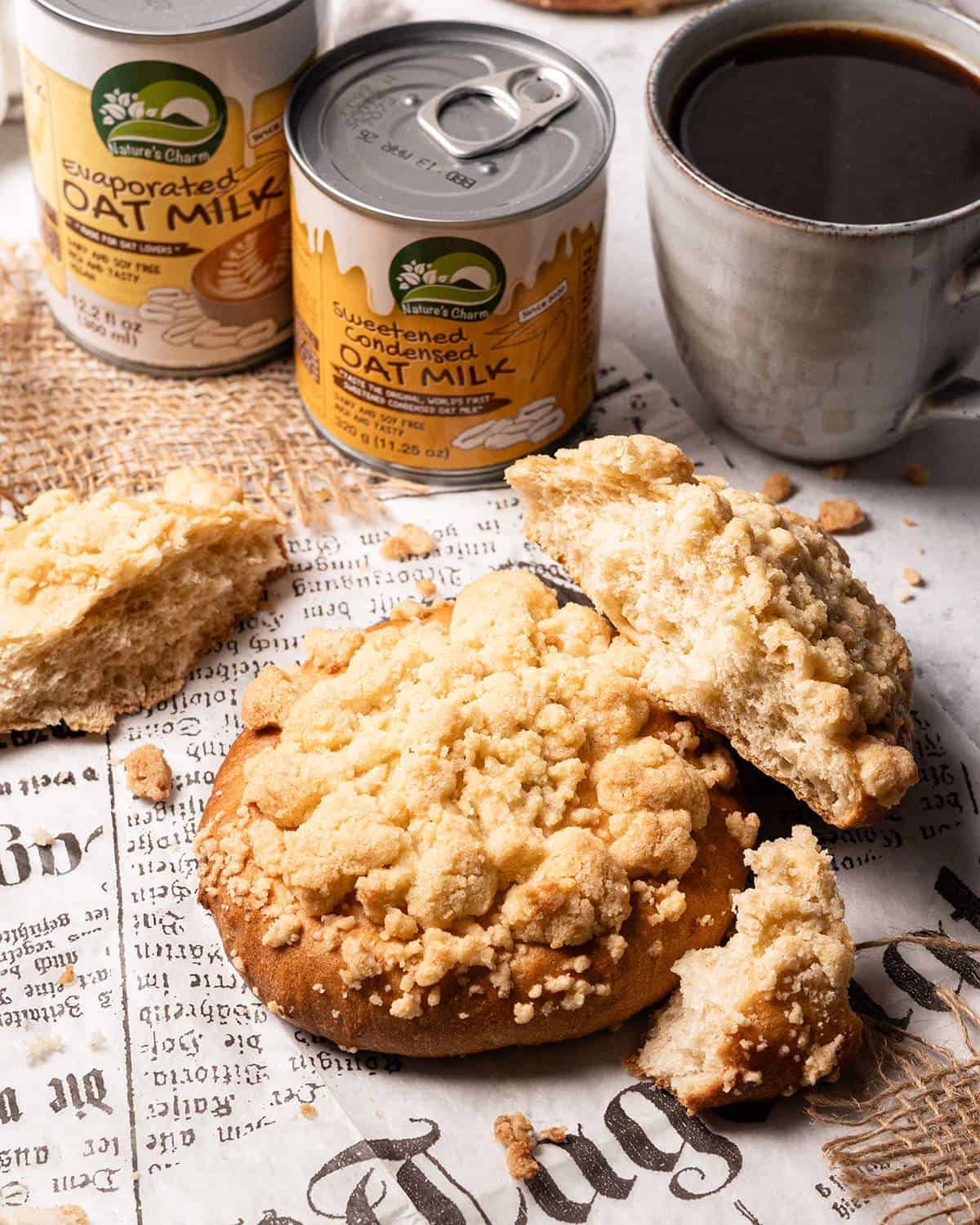 Vegan crumble rolls on parchment paper with one torn apart showing the fluffy dough texture inside besides cans from Nature's Charm.