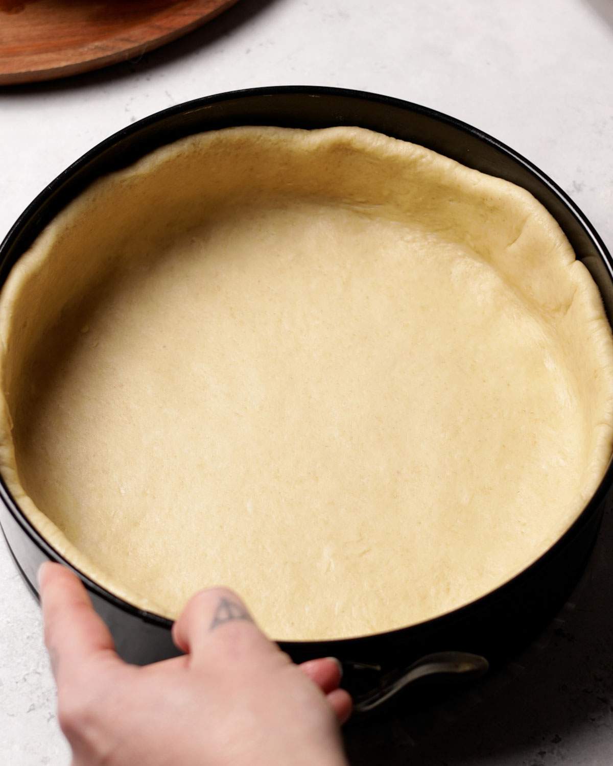 Yeast dough base for rice pudding cake in a springform.