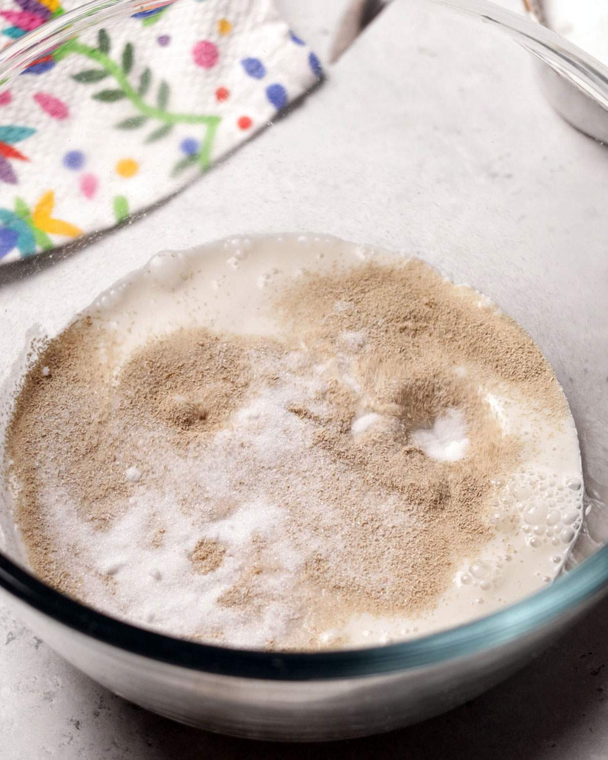 Mix of evaporated oat milk, yeast and sugar in a mixing bowl.