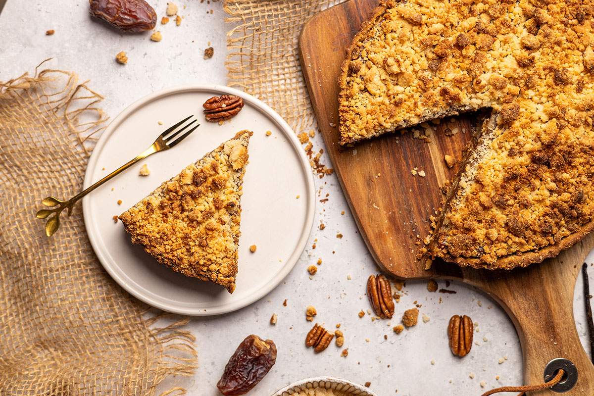 Top view of vegan pecan crumble tart on wooden board.