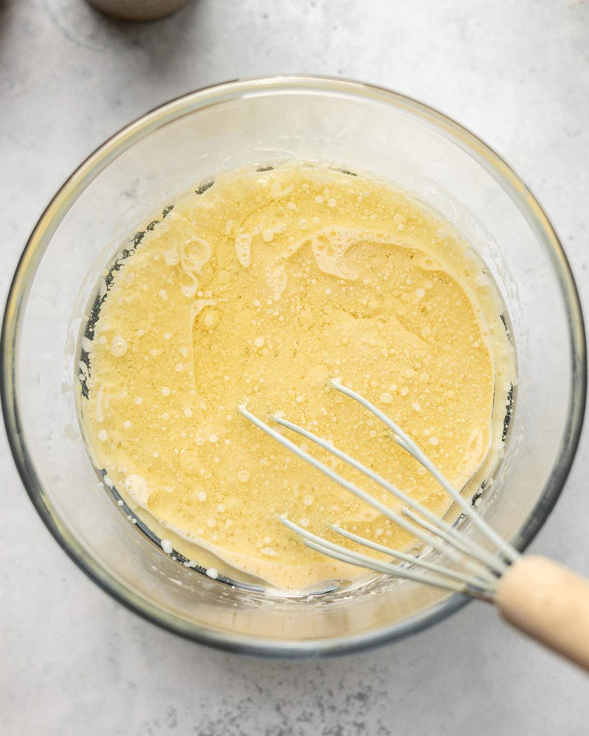 Wet ingredients whisked together in a glass bowl for vegan German apple cake batter.