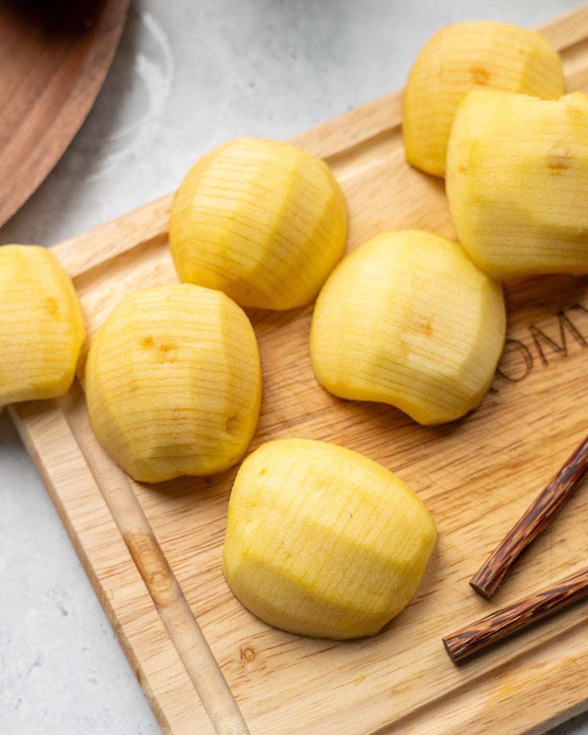 Peeled apples on a wooden board ready for vegan German apple cake.