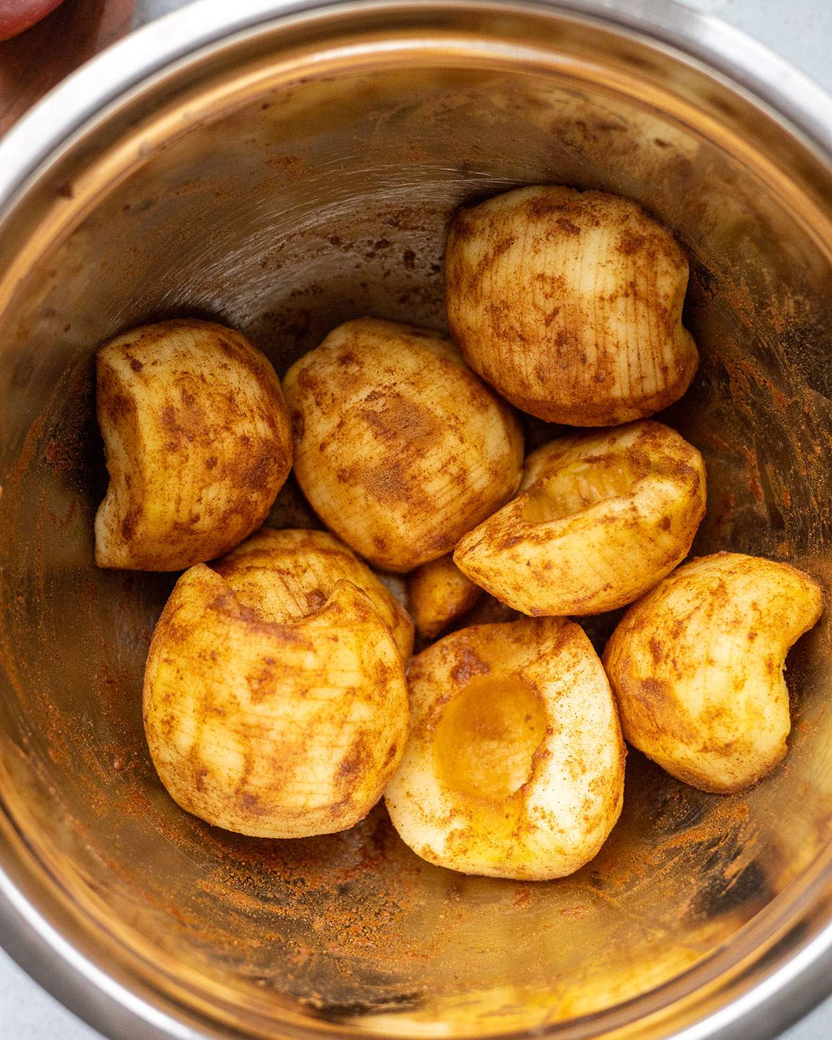 Cinnamon-coated apples in a mixing bowl for vegan apple cake filling.