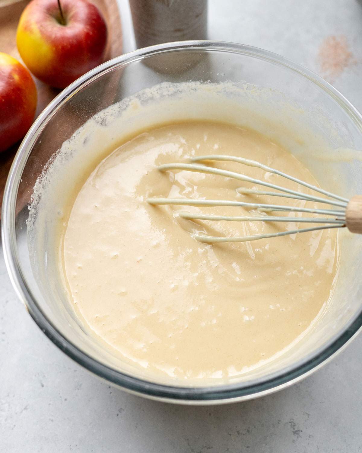 Smooth vegan cake batter whisked in a glass mixing bowl.