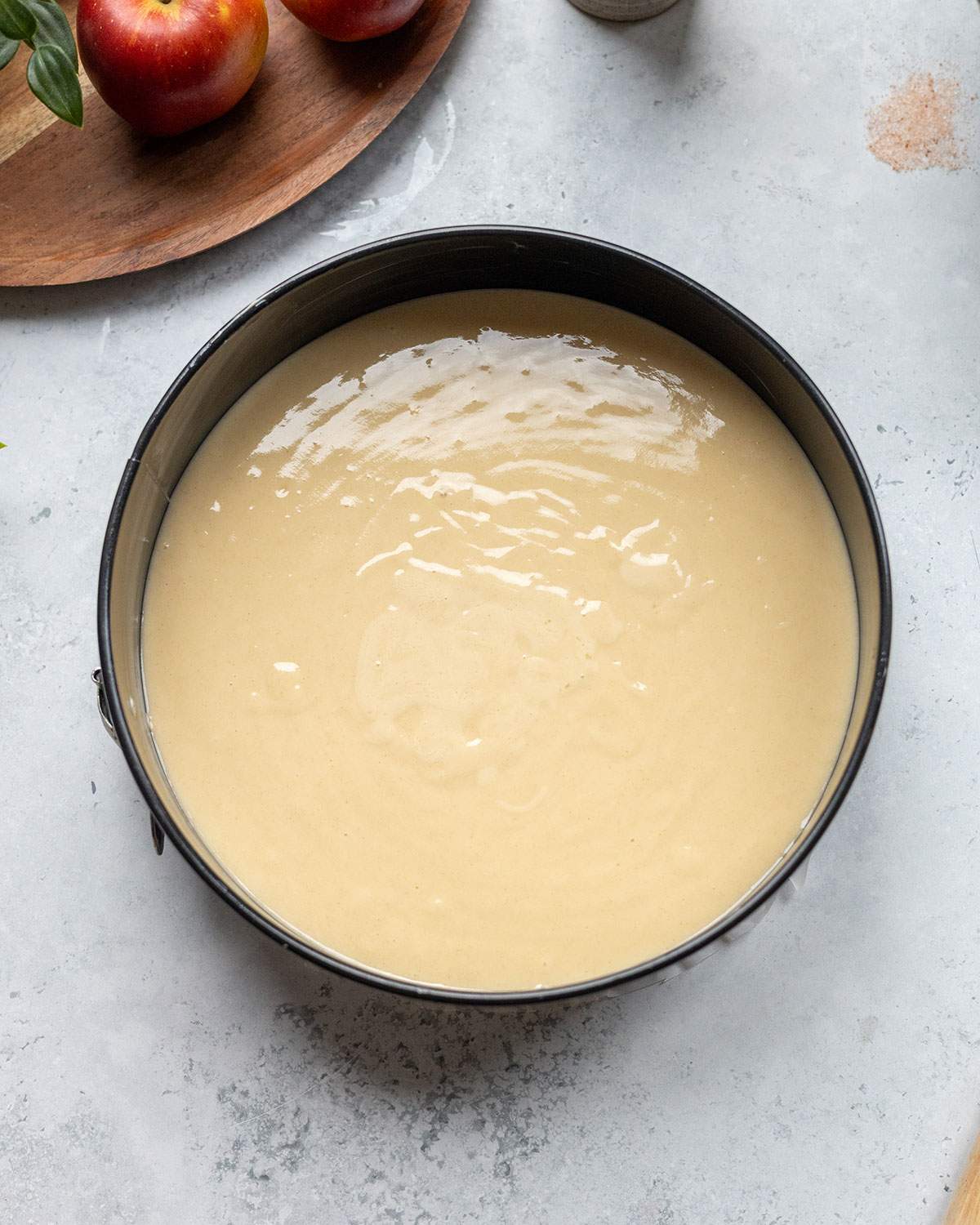Vegan apple cake batter poured into a round springform cake tin.