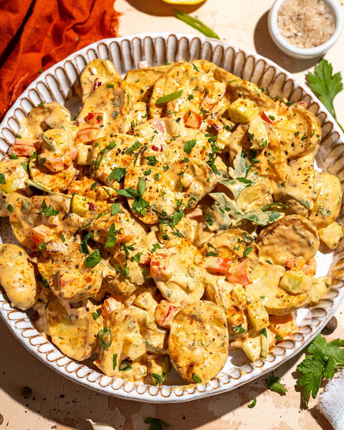 Homemade Cajun potato salad in a serving bowl garnished with fresh herbs and green onions.