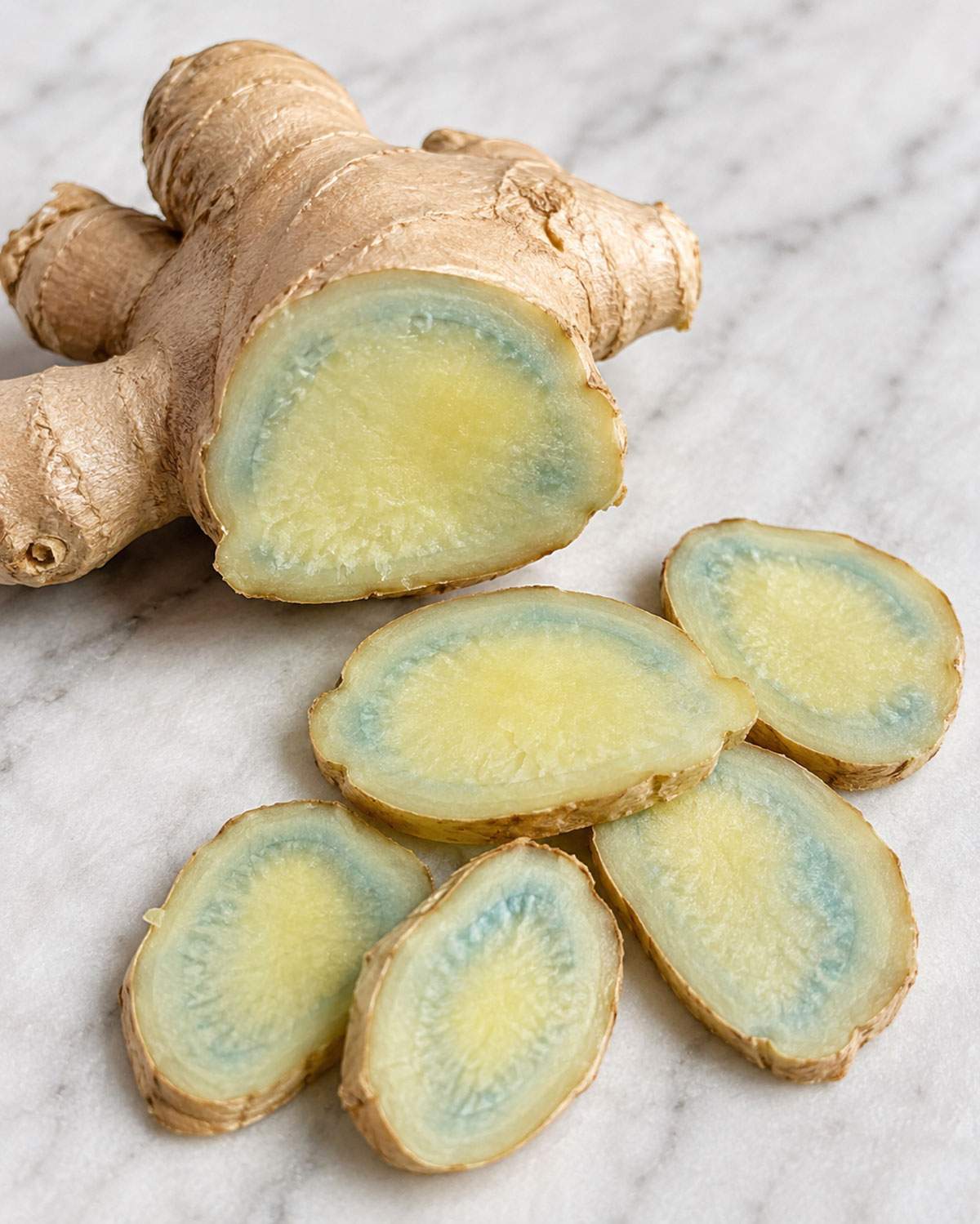 Cut ginger root and slices showing blue-green discolouration around the edges of the flesh.