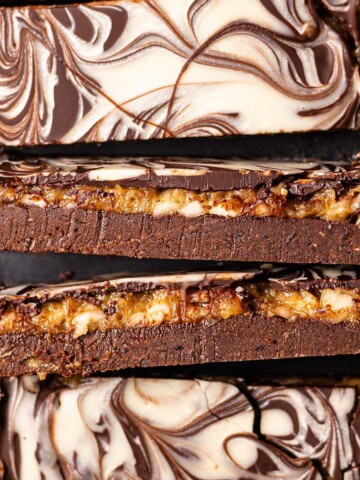 Close-up of date caramel protein bars with a fudgy chocolate base, golden caramel layer, and cream-colored swirls on top.