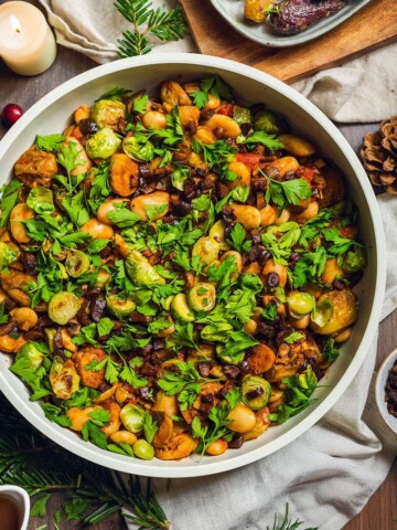Caramelized brussels sprouts in a skillet on the dinner table with fresh herbs on top.